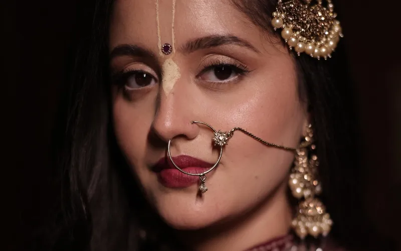 Burgundy Kirtan bridal look with defined eyes, rich lip colour and forehead tika