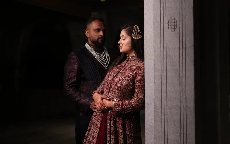 Bride in a burgundy embroidered ensemble with her groom for the Kirtan ceremony